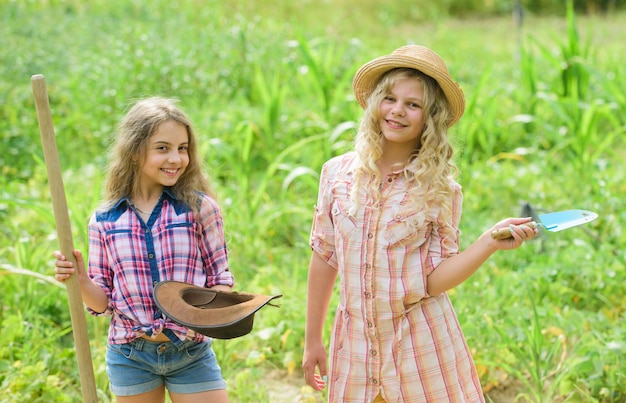 Jardiniers habiles agriculture heureuse printemps campagne jour de la terre été ferme familiale protéger la nature Récolte riche petites filles agriculteur dans le jardin du village les enfants travaillent sur le terrain utiliser un outil de jardinage