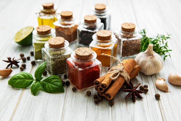 Photo des jarres avec des herbes séchées et des épices sur la table.