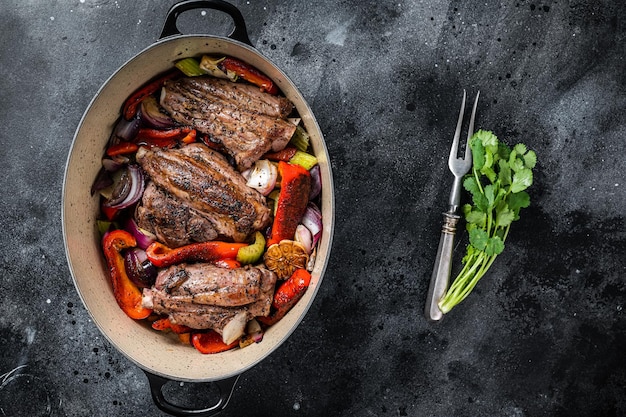 Jarret d'agneau cuit lentement braisé dans une sauce au vin rouge avec des légumes dans une marmite Fond noir Vue de dessus