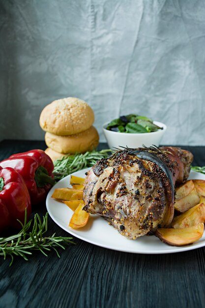 Jarret de porc frit avec pommes de terre servi sur une assiette blanche.