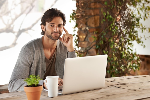 Je commence toujours ma matinée à rattraper mon retard en ligne Portrait d'un beau jeune homme utilisant son ordinateur portable à l'extérieur