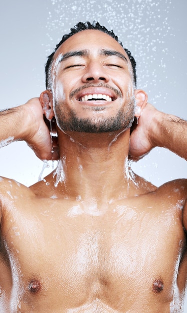 Je me sens toujours rajeuni après une douche Prise de vue en studio d'un beau jeune homme prenant une douche sur un fond gris