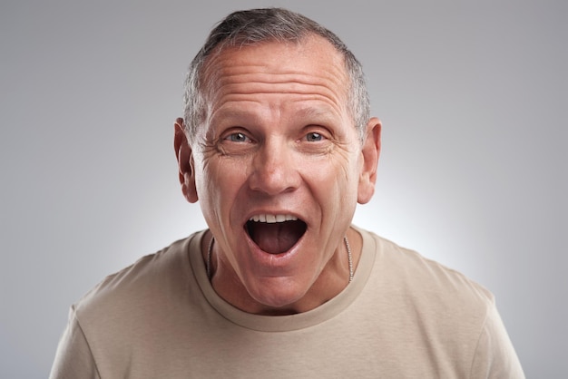 Je n'arrive pas à croire cette photo d'un bel homme mûr debout seul sur un fond gris dans le studio et l'air surpris