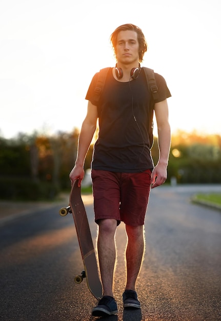 Photo je patine là où je dois être portrait d'un jeune homme debout avec son skateboard à l'extérieur