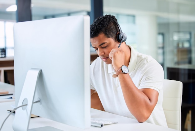 Je peux entendre clairement votre monsieur Photo d'un beau jeune homme d'affaires assis seul dans son bureau et portant un casque tout en utilisant son ordinateur