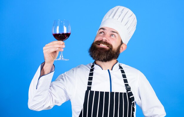 Je recommande ce vin Sommelier masculin confiant examinant un verre avec du vin Ce vin est tout simplement parfait Heureux homme barbu Chef professionnel en uniforme de cuisinier Boisson alcoolisée Vin rouge en verre