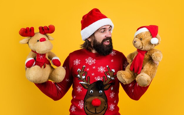 Je souhaite que. joyeux Noël. homme barbu en costume de père noël. hipster célèbre la fête de Noël avec un jouet de renne et d'ours. préparatifs des vacances d'hiver. vente d'achats de cadeaux et de cadeaux. bonne année.