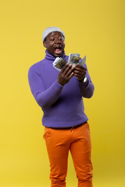 Je suis choqué. Cheerful male personne debout sur fond jaune et regardant son argent