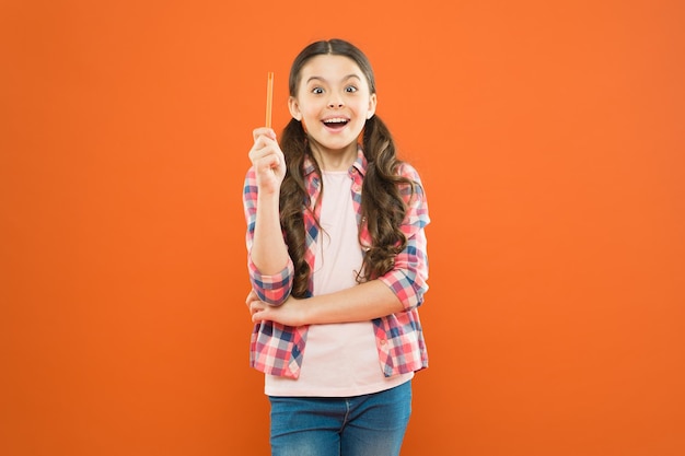 Je suis le génie Fille génie Genius petite écolière a une idée lumineuse sur fond orange Petit enfant pointant le stylo vers le haut ayant une idée de génie