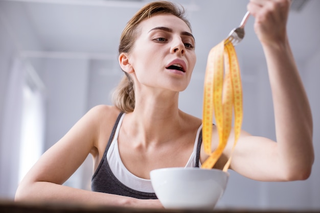 Je suis gros. Belle jeune femme assise à la table en pensant à son poids