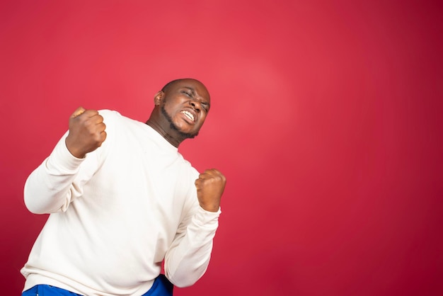 Photo je suis le vainqueur portrait d'un homme afro-américain heureux isolé sur fond rouge.