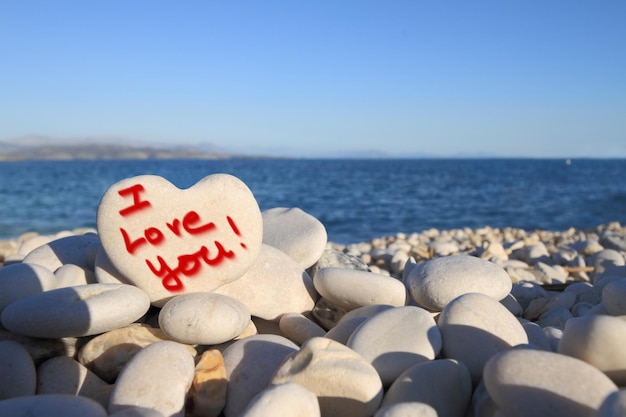 Je t'aime écrit sur une pierre en forme de coeur sur la plage