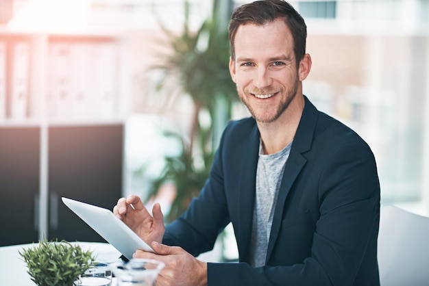 Je vais le faire en un rien de temps Portrait d'un homme d'affaires prospère utilisant sa tablette au bureau