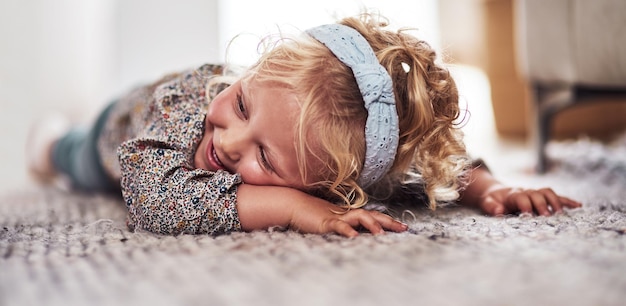 Je vais juste m'allonger ici Photo recadrée d'une adorable petite fille allongée seule sur le sol du salon à la maison