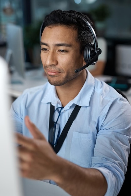 Je vais vous y guider Photo d'un jeune homme utilisant un casque et un ordinateur dans un bureau moderne