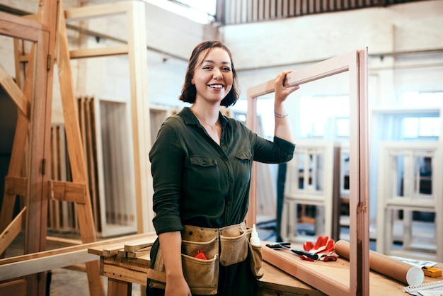 Je viens de commencer un nouveau projet Photo recadrée d'une charpentière tenant un cadre en bois dans son atelier