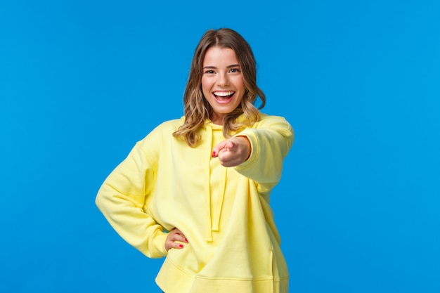 Je vous ai choisis. Confiante et cool jeune fille blonde hipster avec coupe courte, sweat à capuche jaune, pointant le doigt sur la caméra avec une expression sûre d'elle faisant le choix final, invitant à rejoindre l'équipe