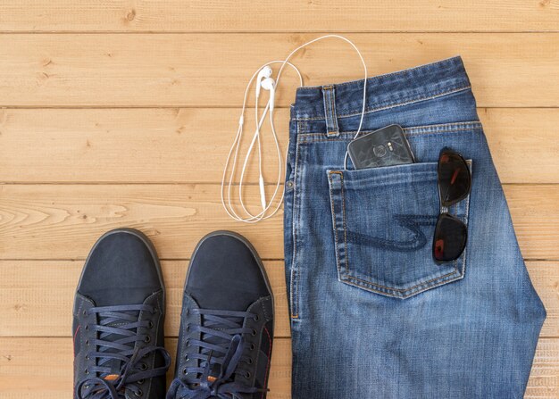 Jeans et accessoires pour hommes sur le plancher en bois.