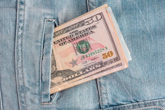 jeans avec des billets en dollars américains dans une poche. Des dollars en jeans. Notion financière.