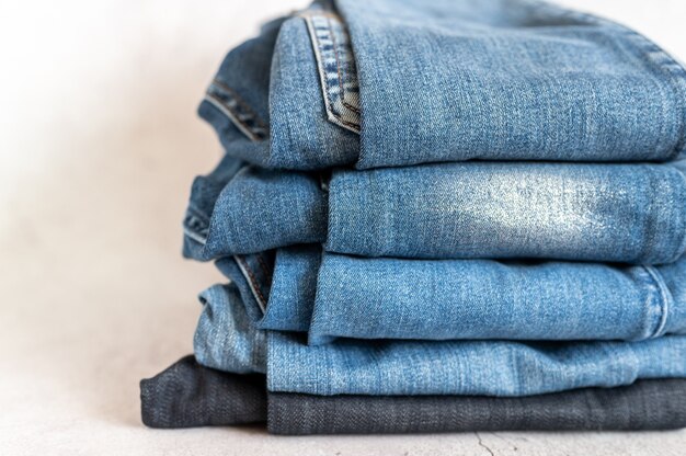 Les jeans sont empilés sur un fond blanc. pile de plusieurs pantalons en denim décontractés toutes saisons pour femmes ou adolescents, vêtements de couleur bleue