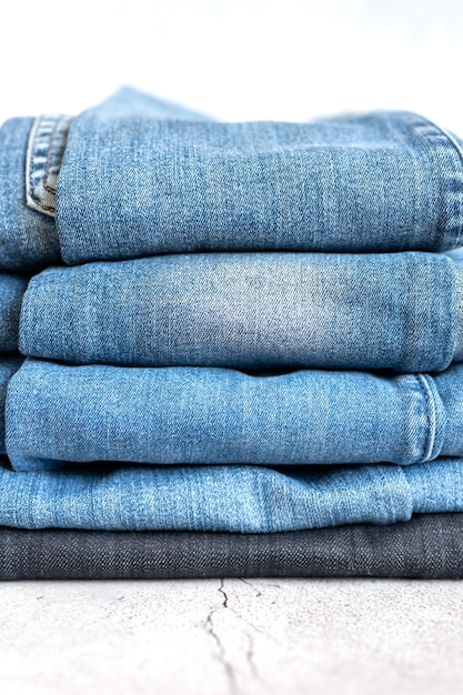 Les jeans sont empilés sur un fond blanc. pile de plusieurs pantalons en denim décontractés toutes saisons pour femmes ou adolescents, vêtements de couleur bleue