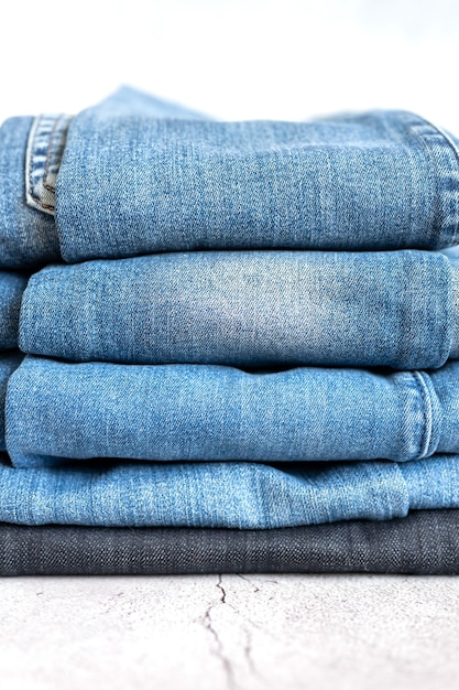 Les jeans sont empilés sur un fond blanc. pile de plusieurs pantalons en denim décontractés toutes saisons pour femmes ou adolescents, vêtements de couleur bleue