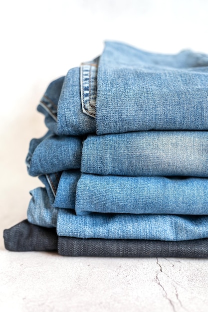 Les jeans sont empilés sur une pile de fond blanc de plusieurs femmes à la mode ou d'adolescentes décontractées