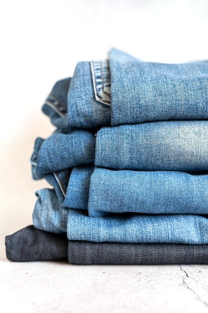 Les jeans sont empilés sur une pile de fond blanc de plusieurs femmes à la mode ou d'adolescentes décontractées