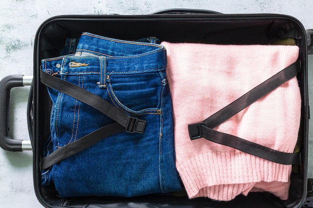 Jeans et vêtements dans les bagages, jeans en vue de dessus de valise, valises d'emballage. Coup de vêtements et de jeans