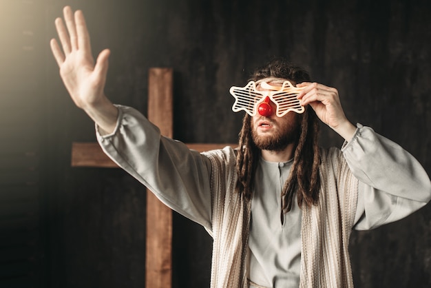 Jésus Christ dans des verres de fête tendant la main, croix de crucifixion sur fond noir