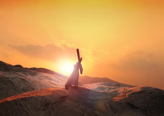 Jésus portant la croix de la souffrance qui symbolise la lumière et les nuages de la colline au coucher du soleil et