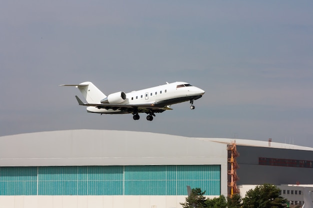 Jet d'affaires décollant sur le fond d'un hangar