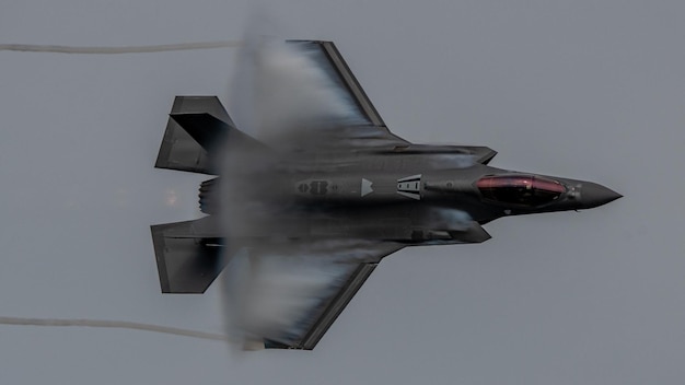 Un jet f-35 vole dans les airs avec de la fumée qui en sort.