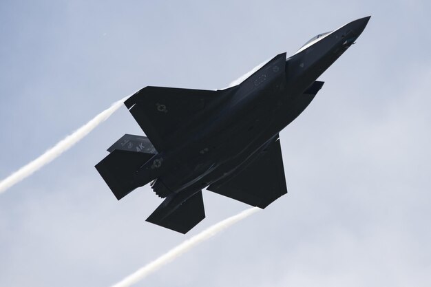 Un jet f-35 vole dans le ciel avec de la fumée qui en sort.