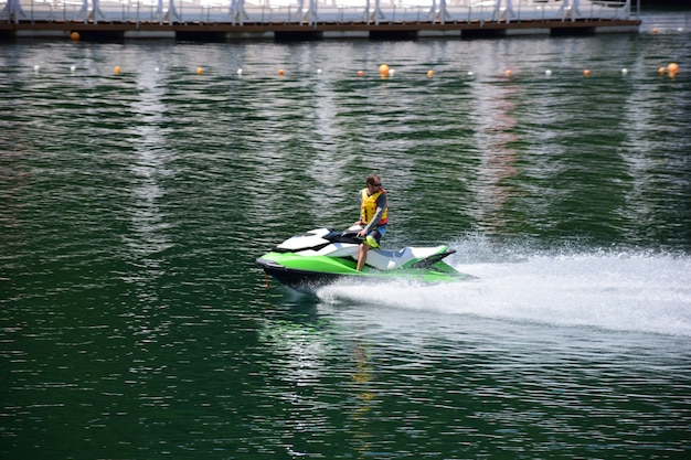 Un jet ski avec un homme dans un gilet de sauvetage flottant dessus se précipite rapidement dans l'eau