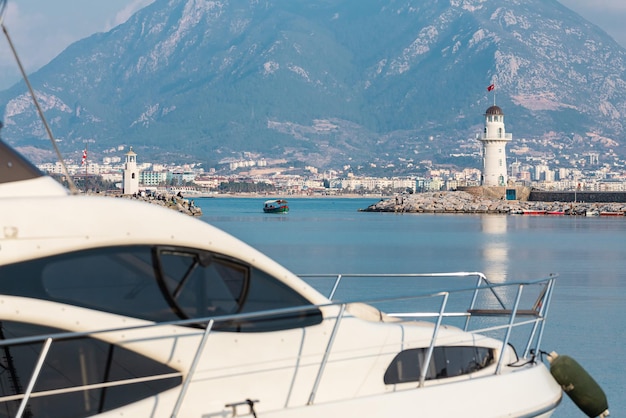 Une jetée avec un beau phare blanc et une jetée avec de nombreux bateaux et yachts sur le fond de la mer bleue