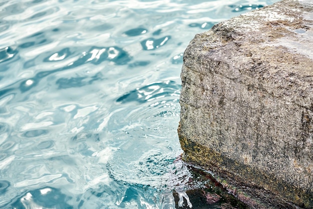 Jetée en béton gris à l'eau de mer bleue avec de petites vagues sous la lumière du soleil le jour d'été à Port