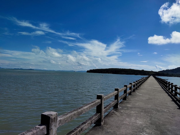 Une jetée en bois avec un ciel bleu et un phare en arrière-plan.