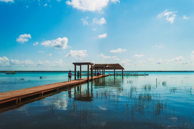 Jetée en bois dans le lagon des sept couleurs avec un beau paysage. Les personnes bénéficiant de l'eau cristalline de la lagune de Bacalar, Quintana Roo, Mexique