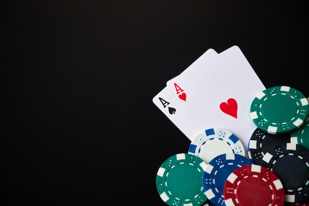 Jetons de casino et cartes à jouer sur fond réfléchissant sombre