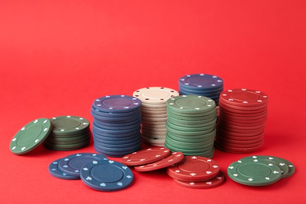 Photo jetons de poker sur un mur rouge. vue de dessus