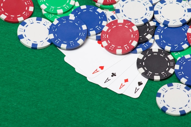 Jetons de poker et quatre as sur un fond de table de casino vert