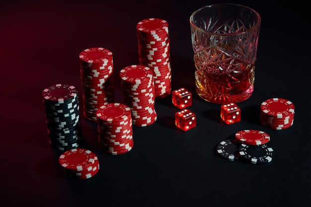 Jetons de poker et verre de vin de cognac sur table sombre. Nature morte. Le concept de jeu. Poker en ligne