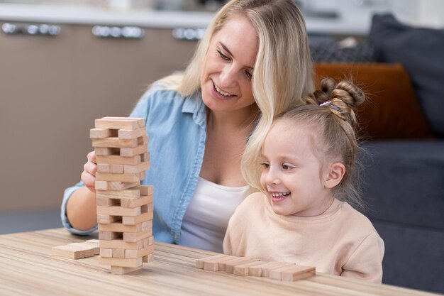 Jeu de blocs de tour en bois Maman et petite fille s'amusant à jouer ensemble à des jeux de société en famille