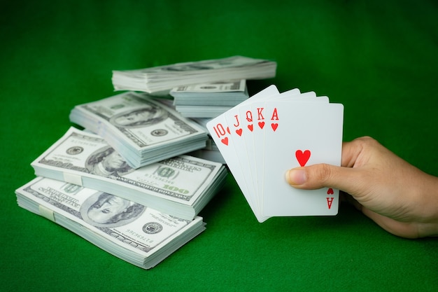 Jeu de casino de poker Royal Straight Flush et la pile d'argent de billets de 100 dollars américains