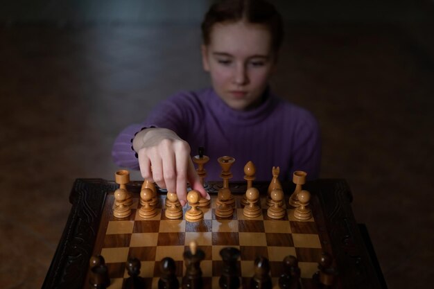 Un jeu d'échecs La fille tient un pion dans ses mains Style photo dramatique sombre dans des couleurs sombres