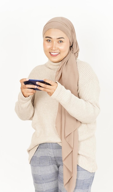 Jeu de jeu sur smartphone de belle femme asiatique portant le hijab isolé sur fond blanc