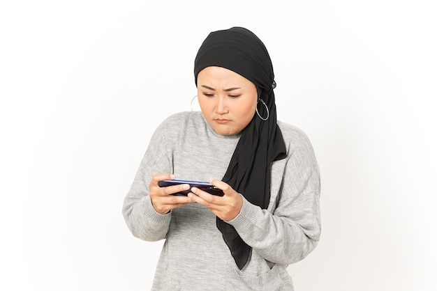 Jeu mobile sur Smartphone de belle femme asiatique portant le hijab isolé sur fond blanc