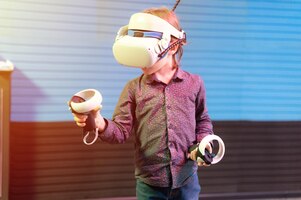 Photo jeu vr et réalité virtuelle kid boy gamer de six ans s'amusant à jouer sur la prise de vue vidéo de simulation futuriste ou explorez le jeu d'étude dans des lunettes 3d et des joysticks dans la salle vr avec une fusée technologique