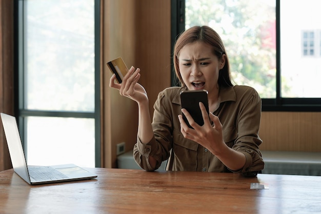 Une jeune acheteuse asiatique mécontente a des problèmes pour acheter en ligne sur Internet sur un smartphone avec une carte de crédit